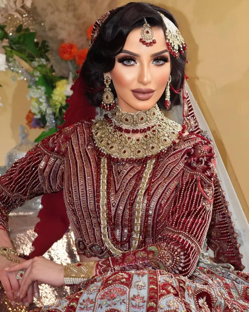 Woman in traditional embroidered outfit with jewelry and floral background
